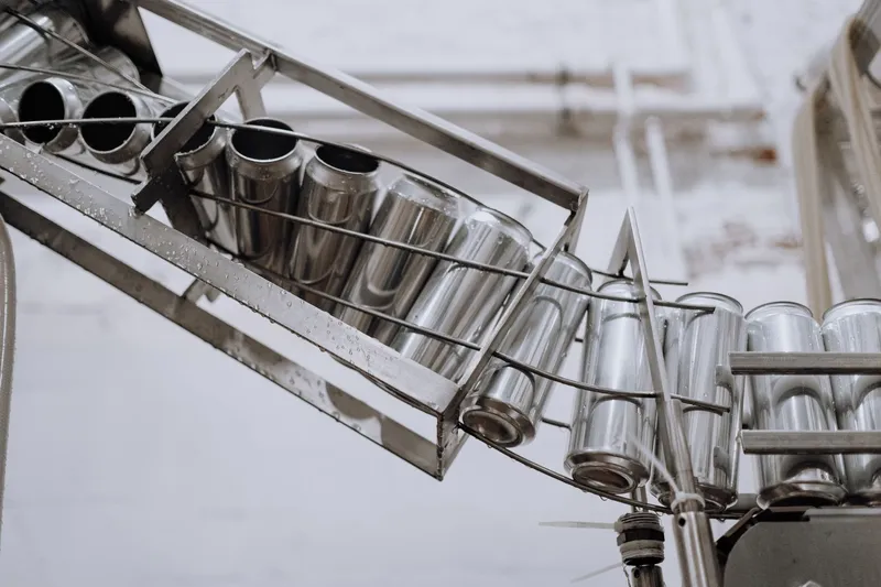 Línea de envasado con latas de aluminio vacías avanzando por una cinta transportadora