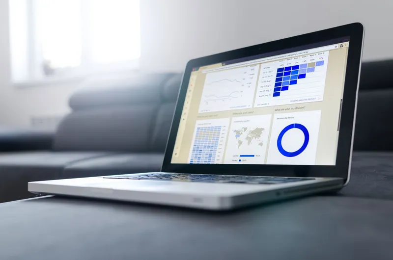 Integración y análisis de datos para empresas: portátil abierto con un cuadro de mando de gráficos, mapas e indicadores en la pantalla