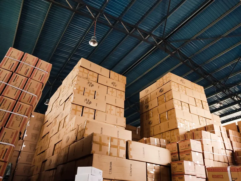 Software, inteligencia artificial y datos para e-commerce: pilas de cajas de cartón apiladas hasta el techo en el interior de un almacén